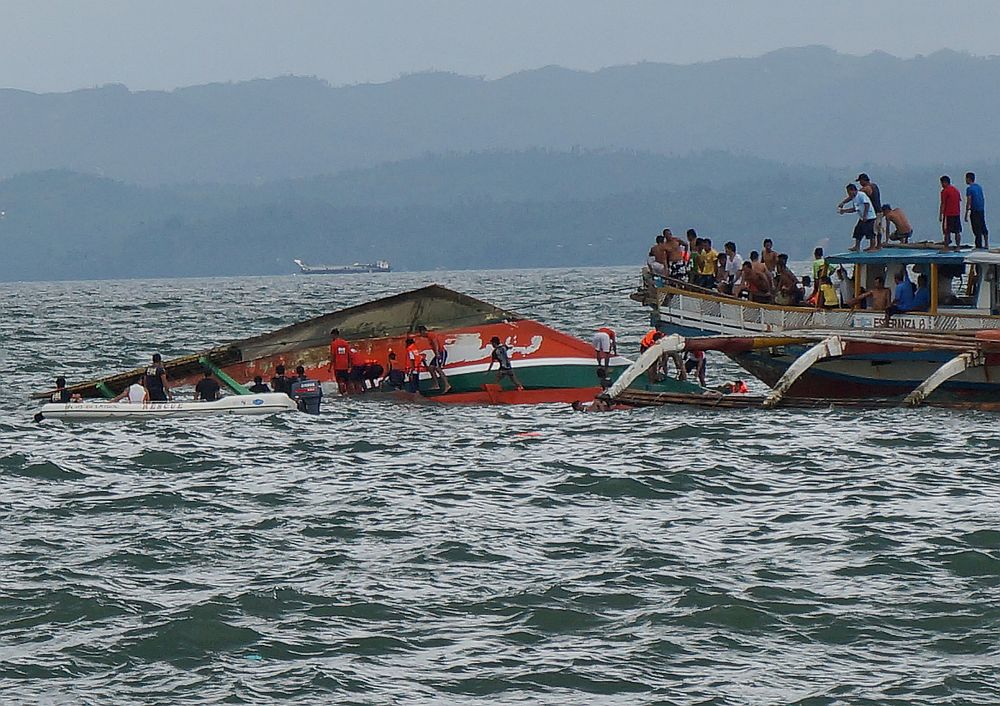 Rescuers help passengers from a capsized ferry boat, center, in Ormoc city on Leyte Island, Philippines, Thursday, July 2, 2015. A ferry capsized Thursday as it left a central Philippine port in choppy waters, leaving dozens dead and many others missing, coast guard officials said. (AP)