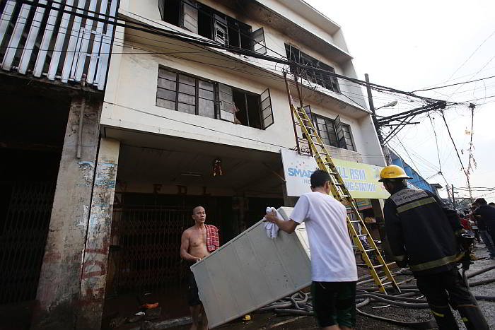 Occupants carry their belongings out of their boarding house that was damaged by fire.(CDN PHOTO/JUNJIE MENDOZA)