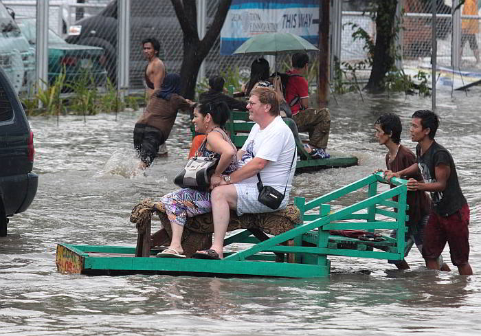 STILL MORE FUN IN PH? A foreign visitor and his wife board a wooden cart for P20 per person to cross knee-deep flood water outside SM City in the North Reclamation Area, Cebu City after Monday’s afternoon downpour lasted over an hour. (CDN PHOTO/ JUNJIE MENDOZA)