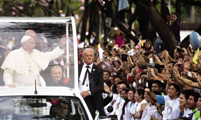 RELIGIOUS FERVOR Pope Francis rides in his popemobile to a stadium in Asuncion, Paraguay, to address religious pilgrims on Saturday. Francis lauded the strength and religious fervor of Paraguayan women while visiting the country’s most important pilgrimage site. (AP)