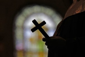 This Dec. 1, 2012 photo shows a silhouette of a crucifix and a stained glass window inside a Catholic Church in New Orleans. A Louisiana Supreme Court decision reaffirmed in May 2014 has revived a sex abuse lawsuit in which parents are suing a priest and a Baton Rouge Catholic diocese for not reporting the alleged abuse when the teenager told the priest about it, and the ruling could have a priest asked to testify about what was said in a private confession. (AP Photo/Gerald Herbert)