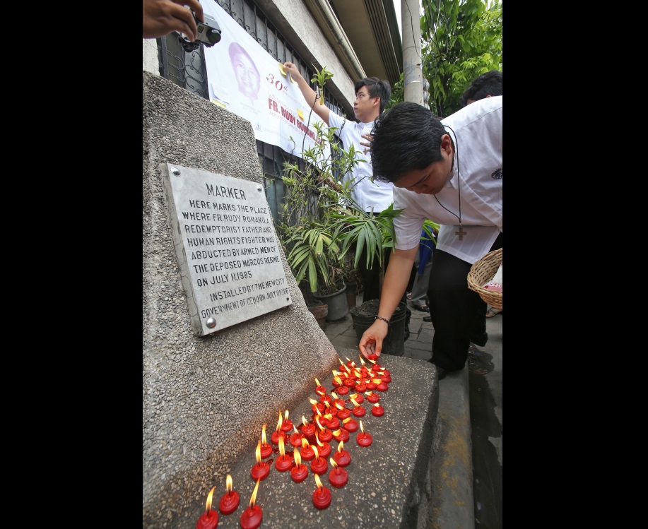 A seminarian of St. Alphonsus Seminary joins other supporters in lighting  candles at the  marker of Fr. Rudy Romano in Tisa,  Cebu City,   where he was abducted 30 years ago during the Marcos administration.  (CDN PHOTO/JUNJIE MENDOZA)