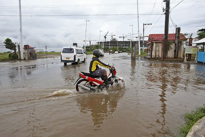  A man on a motorcycle passes through the flooded Mambaling access road to the South Road Properties (SRP). Heavy flooding in the area has been a major cause of concern among SRP locators. CDN FILE PHOTO