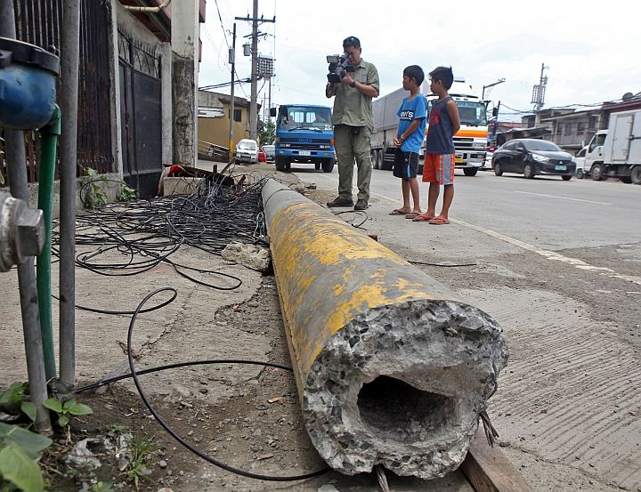 VECO AND PLDT POST COLLAPSE/JULY 08,2015:Cameraman of take photage of the post that collapse that killed a 13 year old boy and injured two others in Mc Arthur blvrd.(CDN PHOTO/LITO TECSON)