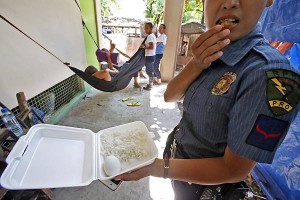 A police officer on APEC security detail  eats her packed lunch of rice, a boiled egg and two pieces of fried lumpia(spring rolls) in   temporary quarters in Mabolo National High School.  (CDN PHOTO/JUNJIE MENDOZA)