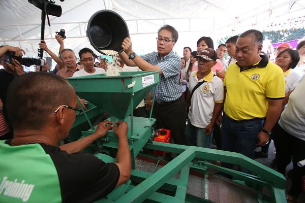 Interior Secretary Mar Roxas (center) pours corn seeds to test a corn mill machine as Gov. Hilario Davide III looks on during yesterday's agri expo at the Capitol grounds. (CDN PHOTO/ JUNJIE MENDOZA)