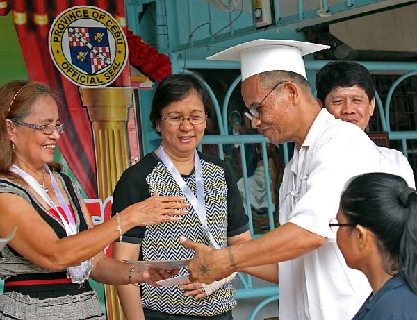 Inmate Larry Biazon receives his diploma from education officials. (CDN PHOTO/ JUNJIE MENDOZA)