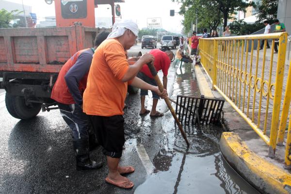 Personnel of the Department of Public Works and Highways (DPWH) clear the drainage at the North Reclamation Area along Pope John Paul II Avenue following a downpour on Monday. (CDN PHOTO/ JUJIE MENDOZA)
