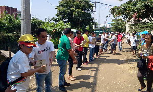 Mandaue Mayor Jonas Cortes, city personnel , students and volunteers  form a human chain to deliver  building materials for a mutli-purpose hall in barangay Tipolo.  (CDN Photo/Norman V. Mendoza)
