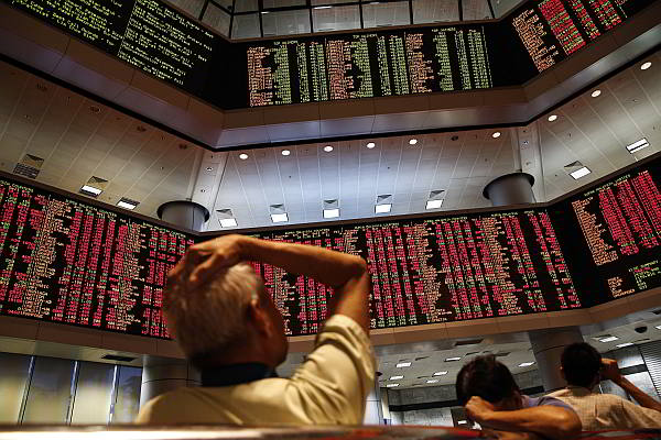 People watch trading boards at a private stock market gallery in Kuala Lumpur, Malaysia on Monday. Stocks tumbled across Asia on Monday as investors, shaken by fears of a China-led global economic slowdown and Wall Street sell-off, unloaded shares in practically every sector.  (AP Photo)