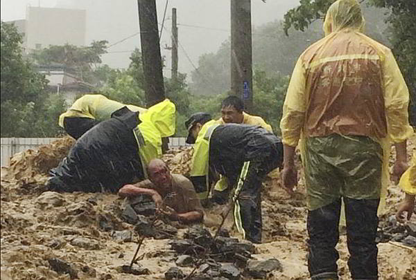 Taipei rescue workers dig out a man trapped from a flash mudslide caused by the typhoon in Xindian, New Taipei City. (AP)
