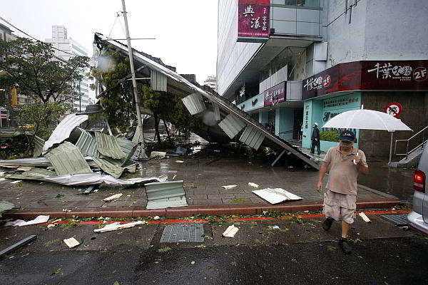 A man passes a damaged structure after Typhoon Soudelor slammed into Taipei, Taiwan on Saturday. (AP)