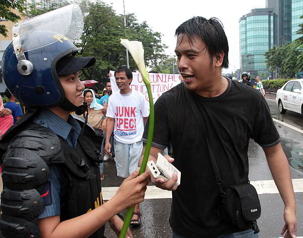 FLOWER POWER. A female police officer  offers  a white gladiola  to Niño Olayvar, vice president of   Anakbayan-Cebu chapter during a rally in front of Radisson Blu where APEC meetings took place. (CDN Photo/Junjie Mendoza)