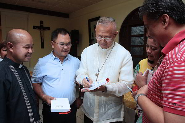 Cebu Archbishop Jose S. Palma (center) signs copies of his biography  written  by Jose Maria de Nazareno, pen name of Fr. Sid Marinay (left), during last Friday’s launching at the Archbishop’s Residence.  (CDN Photo/Junjie Mendoza)