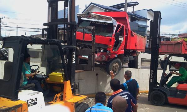 Forklifts are used to remove the wayward dump truck, which almost drove off the Maguikay flyover in Mandaue City. (CDN PHOTO/ NORMAN MENDOZA)
