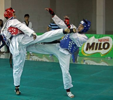 Luigi Estrada of Team Visayas (left) slungs it out with an NCR foe in secondary taekwondo competition.