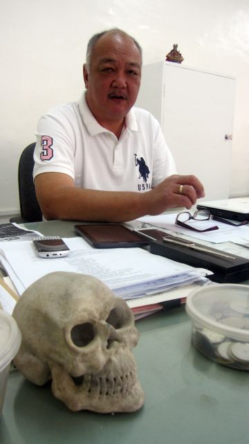 Dr. Rene Cam in his NBI office in barangay Capitol Site, Cebu City. On his desk is a miniature model of human skull made of cement he bought 12 years ago in a cemetery. (CDN PHOTO/ADOR MAYOL)