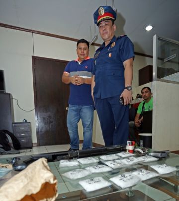 Supt. Artemio Ricabo (right), deputy chief of operations of the Cebu City police, and Supt. Romeo Santander present the packs of suspected shabu and firearms seized from two wanted men in San Fernando town. (CDN PHOTO/LITO TECSON)