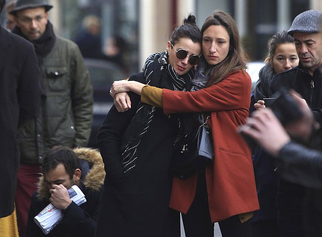 Women comfort each other as they stand in front of the Carillon cafe, in Paris, Saturday, Nov.14, 2015. French President Francois Hollande vowed to attack Islamic State without mercy as the jihadist group admitted responsibility Saturday for orchestrating the deadliest attacks inflicted on France since World War II. (AP Photo/Thibault Camus)