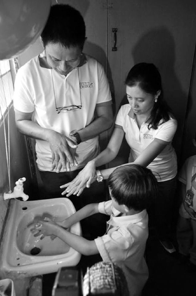 MCWD acting general manager Noel Dalena and public affairs department manager Charmaine Rodriguez-Kara teach a pupil the correct hand-washing technique during the Global Hand-washing Day celebration in the First Assembly of God Christian School in Cansojong, Talisay City.