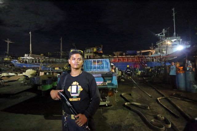 A security guard of Seaford shipyard in Mandaue Negros Waterfront Corp. in Mandaue City. mans the entrance of the shipyard where a cargo ship caught fire yesterday. (CDN PHOTO/JUNJIE MENDOZA)