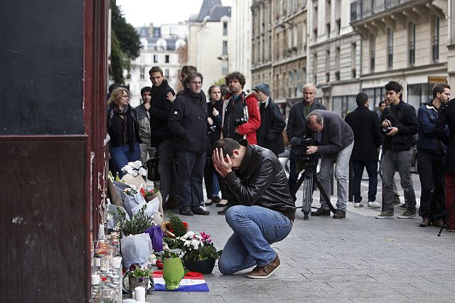 A man holds his head in his hands as he lays flowers in front of the Carillon cafe, in Paris, Saturday, Nov.14, 2015. French President Francois Hollande vowed to attack Islamic State without mercy as the jihadist group admitted responsibility Saturday for orchestrating the deadliest attacks inflicted on France since World War II. (AP Photo/Thibault Camus)