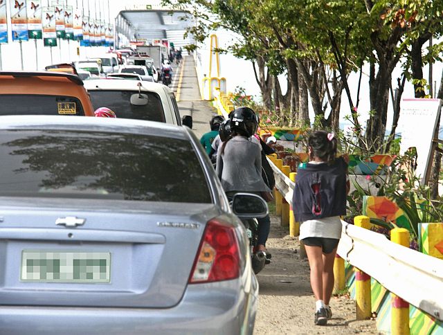 SILOY IS WATCHING: A young pedestrian had to walk on the very side of the temporary sidewalk on her way to the old Mactan-Mandaue Bridge to avoid hitting from the moving vehicles using the bridge. ATTENTION: BRIDGE MANAGEMENT BOARD MAY BE ITS TIME TO MAKE A SIDE WALK ON THE AREA TO AVOID ACCIDENT.