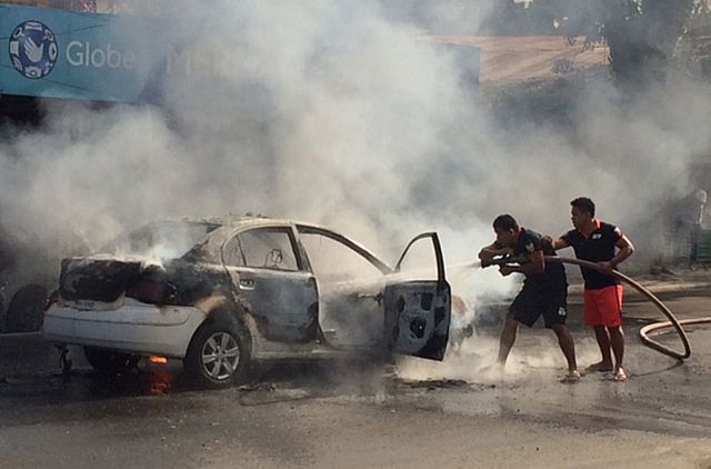 CAR FIRE/NOV 18,2015: Firemen train their hose to a burning car along F. Cabahug brgy Mabolo Cebu City. A taxi was caught on fire yesterday afternoon at along F. Cabahug St. Both the driver and the passenger are all safe.  CONTRIBUTED PHOTO/MAX LUWELL OTADOY)