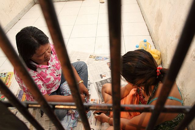 Emma Leocadio sits behind bars with her daughter Sherryl after their arrest on Aug. 5, 2011 for transporting 15 children from Getafe, Bohol.