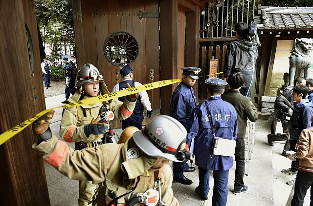 Firefighters and police officers inspect the south gate of Yasukuni shrine in Tokyo after an explosion was reported at the shrine. (AP PHOTO)
