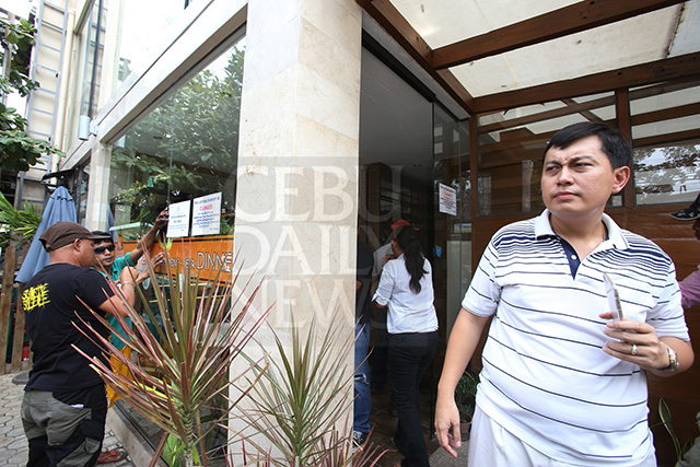 Businessman Adrian Lee, owner of Camia Street Cafe and Resto, watches as City Hall team shuts down his establishment in barangay Capitol Site in this July 9, 2015 file photo.