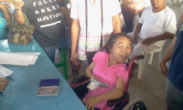 Baby Jane Torion, 15, a girl who has cerebral palsy from barangay Marigondon, is all smiles after receiving her P2,000 cash gift from the Lapu-Lapu City government during yesterday's distribution of financial aid to senior citizens and people with disabilities at the City Sports Complex. (CDN PHOTO/NORMAN MENDOZA)