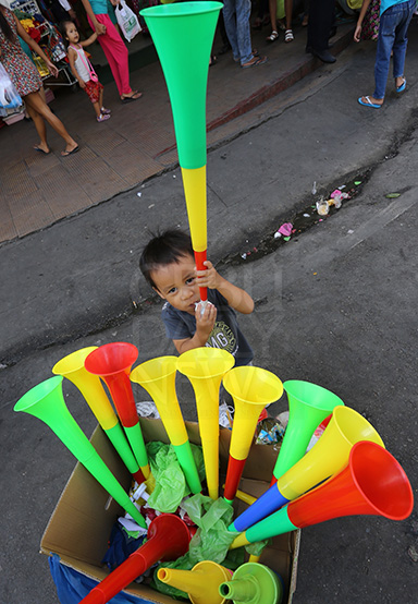 A boy tries out a "torotot" that his parents bought from a street vendor in Osmena Boulevard, Cebu City. (CDN PHOTO/JUNJIE MENDOZA)
