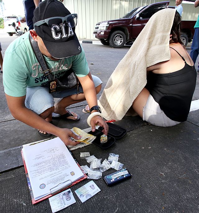 P1.1 MILLION WORTH OF SHABU/DEC. 12, 2015: A CIDG7 agent inventories the confiscated illegal drugs Shabu worth more that P1 Million,P4,000 cash confiscated from Marry Ann C. Ruta 33 (covering her face) in a buy-bust operation with CIDG7 agents at Sumilong  corner Camiguin Road Cebu Business Park barangay Hipodromo, Cebu City.(CDN PHOTO/JUNJIE MENDOZA)