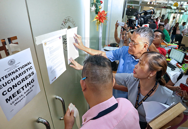 A 60-day preventive suspension order against Cebu City Mayor Michael Rama is served by Rene Burdeos (2nd from right), regional director of the Department of Interior and Local Government (DILG-7) and lawyer Aiiza Fiel A. Arcenal-Nogra who tape it on the glass door of the mayor's office in City Hall. The mayor's staff refused to receive the document. The DILG said posting the order was sufficient. (CDN PHOTO/JUNJIE MENDOZA)