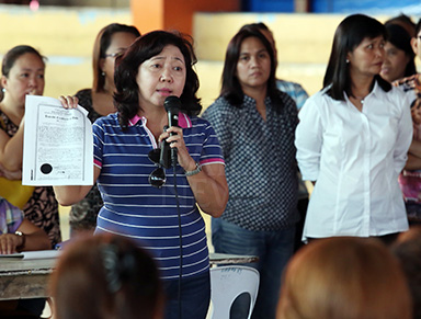 UNIVERSITY OWNER. UP Cebu Dean Liza Corro shows a photo copy of the university's land title for a 2.6 hectares area in barangay Lahug, including the burned site in sitio Avocado. In her dialog with fire victims at the Lahug Elementary School, she offered a relocation site in Nivel Hills. Cebu City Councilor Mary Ann Delos Santos (right) and acting Lahug barangay Captain Ging-ging Muana attended the dialog. (CDN PHOTO/JUNJIE MENDOZA)