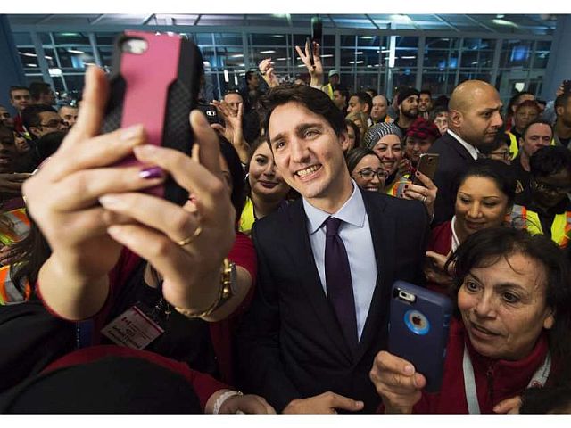 Canadian Prime Minister Justin Trudeau poses for selfie with workers before he greets refugees from Syria at Pearson International airport, in Toronto. (AP PHOTO)