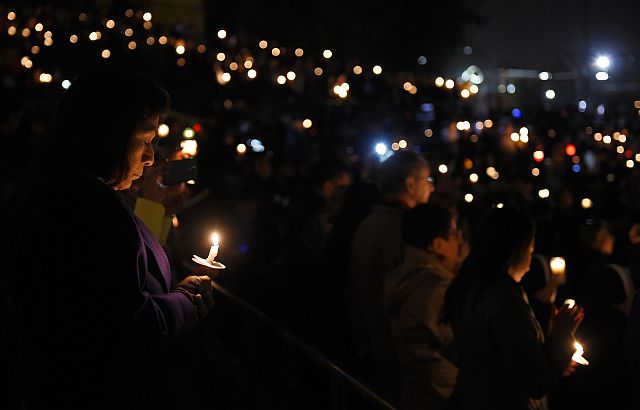 People hold candles during a vigil for shooting victims  at San Manuel Stadium in San Bernardino, California. (AP PHOTO)