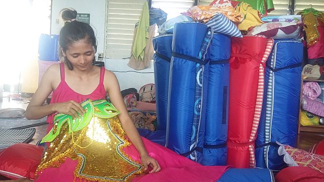 Liberty Bonafe, one of the dancers of Catbalogan contingent, checks on her costume for Sunday's street dancing. They are occupying a classroom of Cebu City Central School  for the weekend. (CDN PHOTO/APPLE TA-AS)