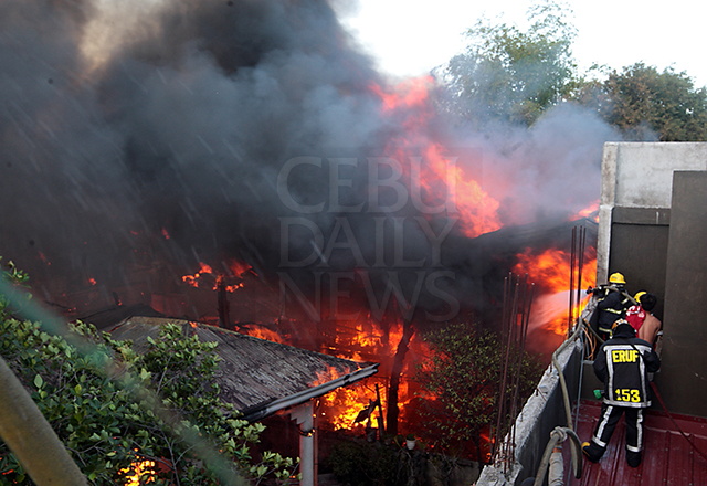 Firefighters train their hose at the raging fire in purok Nangka, barangay Ibaba0-Estancia, Mandaue City. (CDN PHOTO/TONEE DESPOJO)