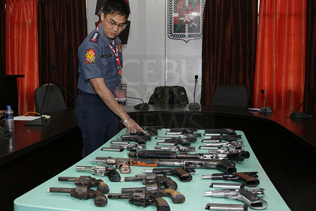 Senior Supt. Cliffor Gaeranod examines the firearms that were seized in two separate raids in Danao City, northern Cebu. ( CDN PHOTO/ LITO TECSON)
