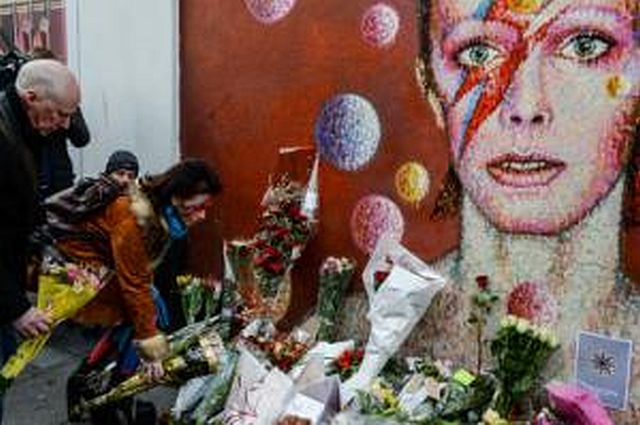 People lay flowers in front of a mural of singer David Bowie, painted by Australian street artist James Cochran, aka Jimmy C, following the announcement of Bowie’s death in Brixton, south London. (AFP PHOTO)