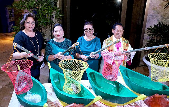 Instead of a ribbon to cut, there was a fishing rod for the fresh catch by, from left: Julie Najar, Jessica Avila, Vice Governor Agnes Magpale and Msgr. Roberto Alesna.