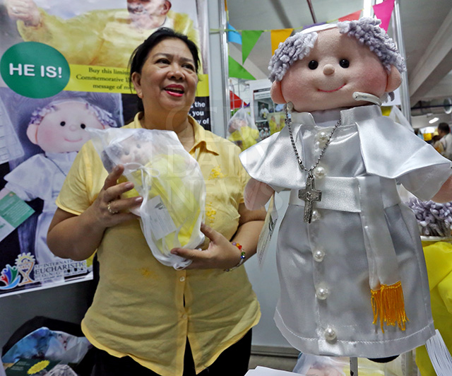 Belen Santos, a member of Lasalian Catechetical Center (DLSU) Manila, shows the Pope dolls at an IEC Pavilion stall. (CDN PHOTO/JUNJIE MENDOZA)