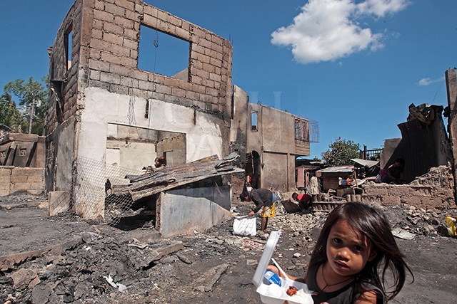 ON HOLD. A girl carries her packed lunch while walking past the gutted homes in Quiot. (CDN PHOTO/TONEE DESPOJO)