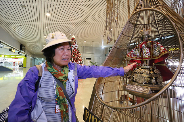 Mildred Bongato, a first-time visitor of Cebu touches the image of the Sto. Niño at the airport. (CDN PHOTOS/JUNJIE MENDOZA)