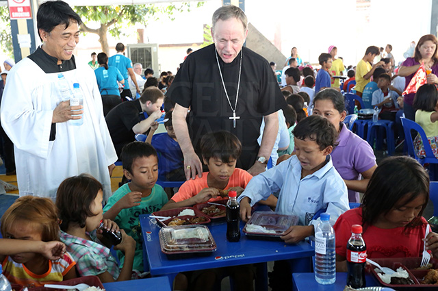 Archbishop Michael Miller of Vancouver, Canada (in black) joins children at the Table of Hope, a lunch shared with almost 1,000 children and their parents who come from poor families in Metro Cebu. They were served "humba" (pork stew), fried chicken and rice, a meal following a Mass to involve the "poorest of the poor" in the 51st Eucharistic Congress which formally opens today in Cebu City. (CDN PHOTO/JUNJIE MENDOZA)