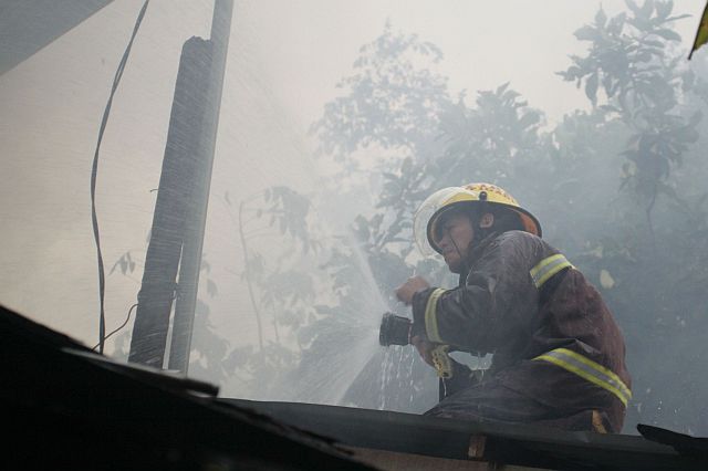 A fireman train his hose to a burning house in Duljo Fatima. (CDN PHOTO /Lito Tecson)