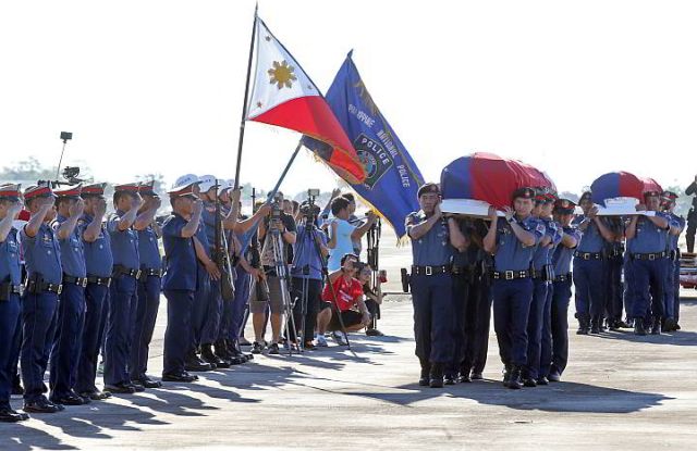Police officers salute the coffins bearing the remains of Special Action Force (SAF) troopers PO2 Windel Candano and PO1 Romeo Cempron that arrived at the Mactan Cebu International Airport.