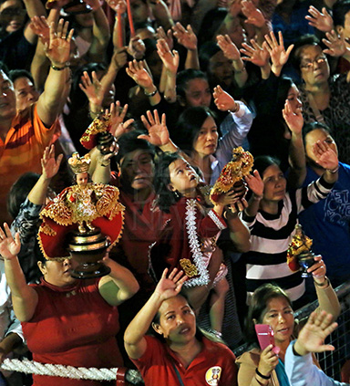Amidst the crowd, a boy dressed in the red robes of the Sto. Nino, lifts his own religious icon as the faithful sing the hymn "Bato Balani" and wave their hands in the air. (CDN PHOTO/JUNJIE MENDOZA)